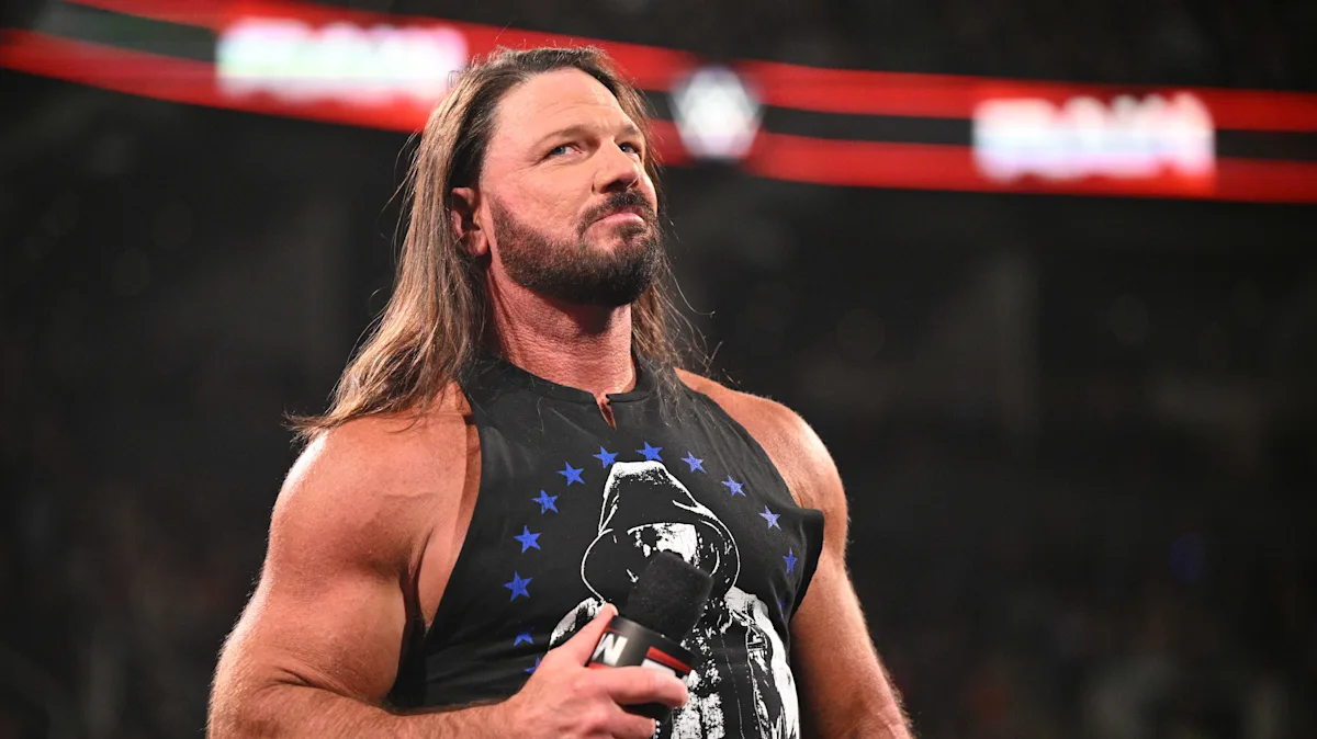 AJ Styles sostiene un micrófono dentro del ring de WWE mientras observa al público durante un segmento en Monday Night Raw.