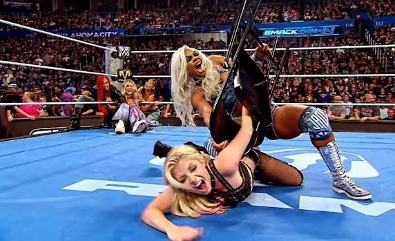 Jade Cargill aplica una llave de sumisión sobre Alexa Bliss durante un ataque en WWE SmackDown, mientras varias luchadoras observan desde el fondo del ring.