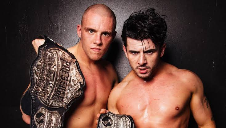Judas Icarus y Travis Williams, integrantes de Sinner & Saint, posan con cinturones de campeonato en pareja