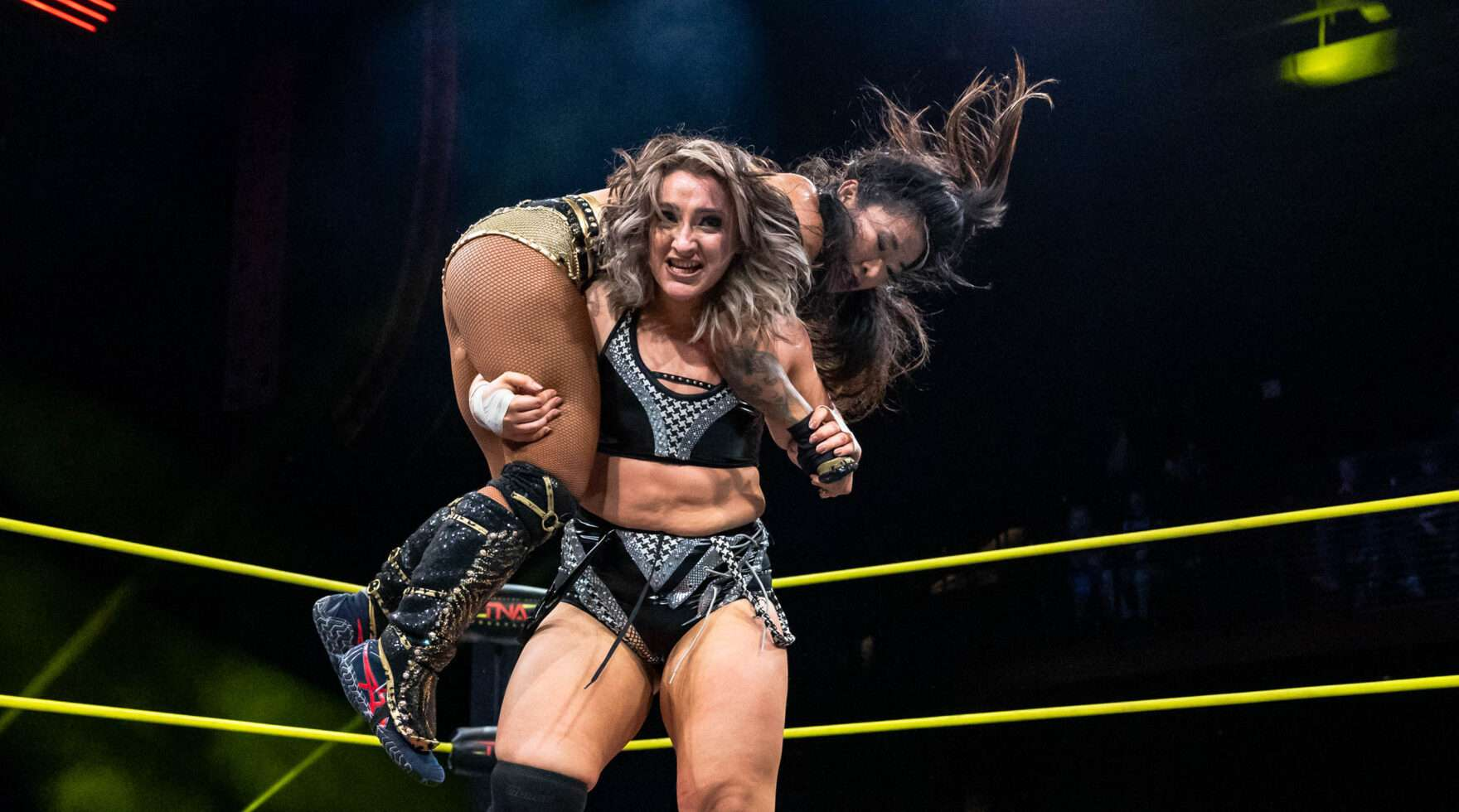 Dani Luna carga sobre sus hombros a Lei Ying Lee durante una lucha en TNA Wrestling.