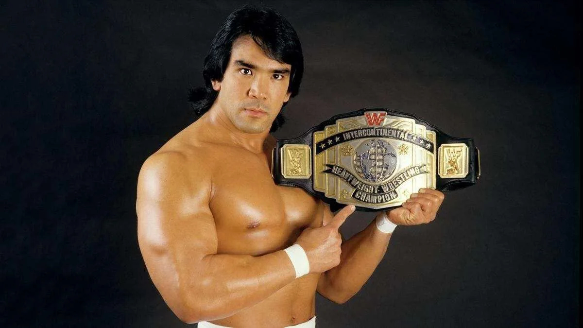 Ricky «The Dragon» Steamboat sostiene y señala el Campeonato Intercontinental de WWF mientras posa sobre un fondo negro.