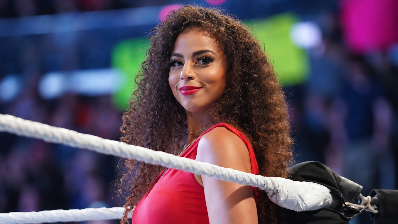 Samantha Irvin con un vestido rojo dentro del ring de WWE durante su labor como anunciadora.
