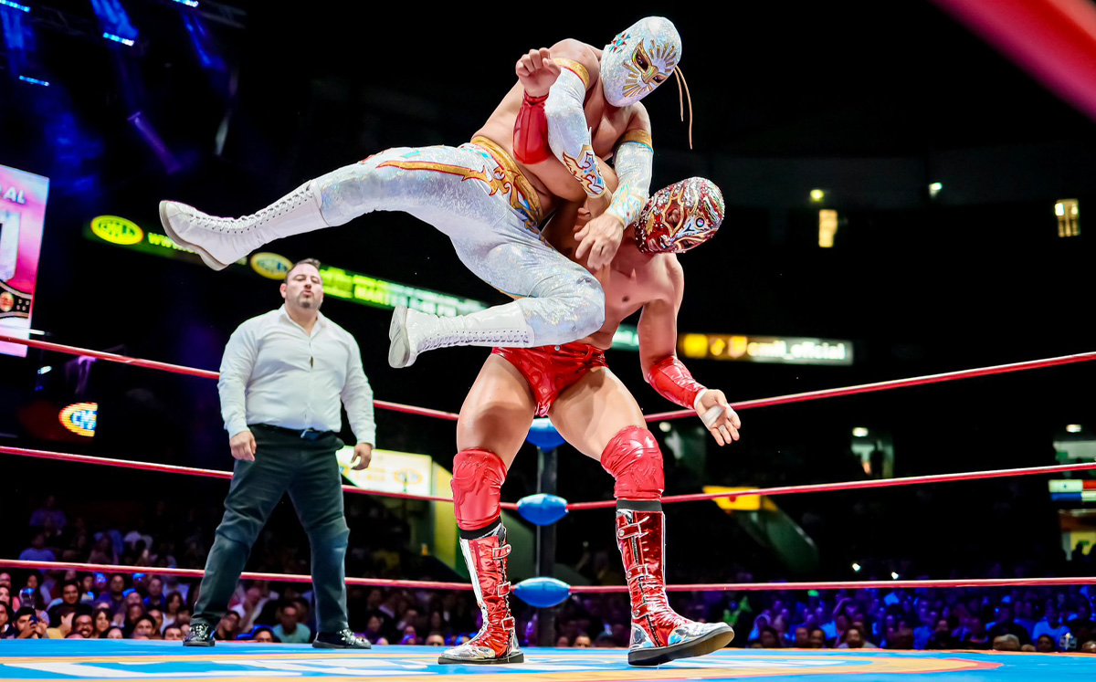 Místico y Titán protagonizan un enfrentamiento en el cuadrilátero del CMLL, mientras uno de los luchadores ejecuta una maniobra sobre su rival.